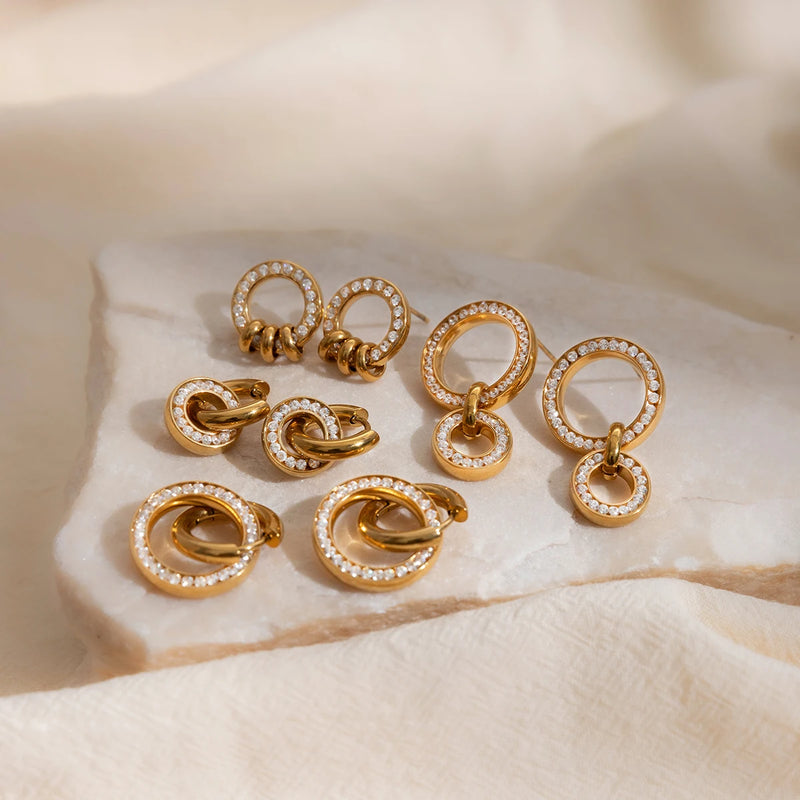 Several crystal-set circle link earrings on cream fabric