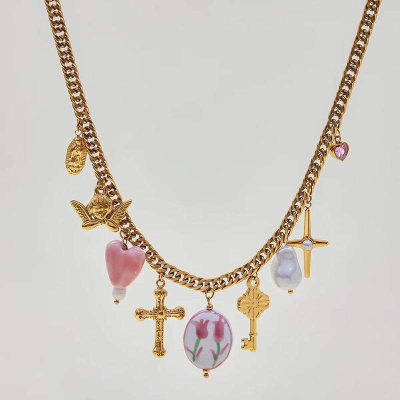 Charm necklace with a cross, key and pink stones, laid flat