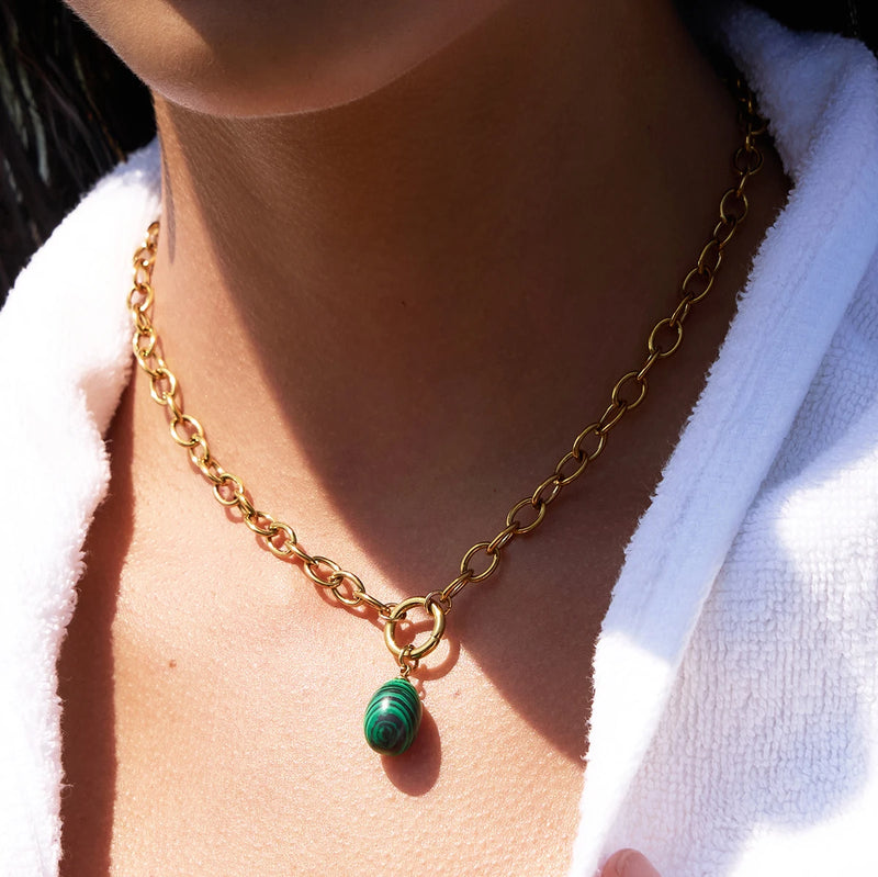 Close view of the green stone drop on a chunky gold-tone chain