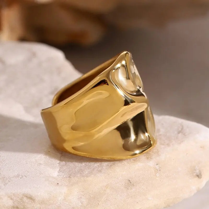 Close view of the gold-tone molten band ring on pale stone