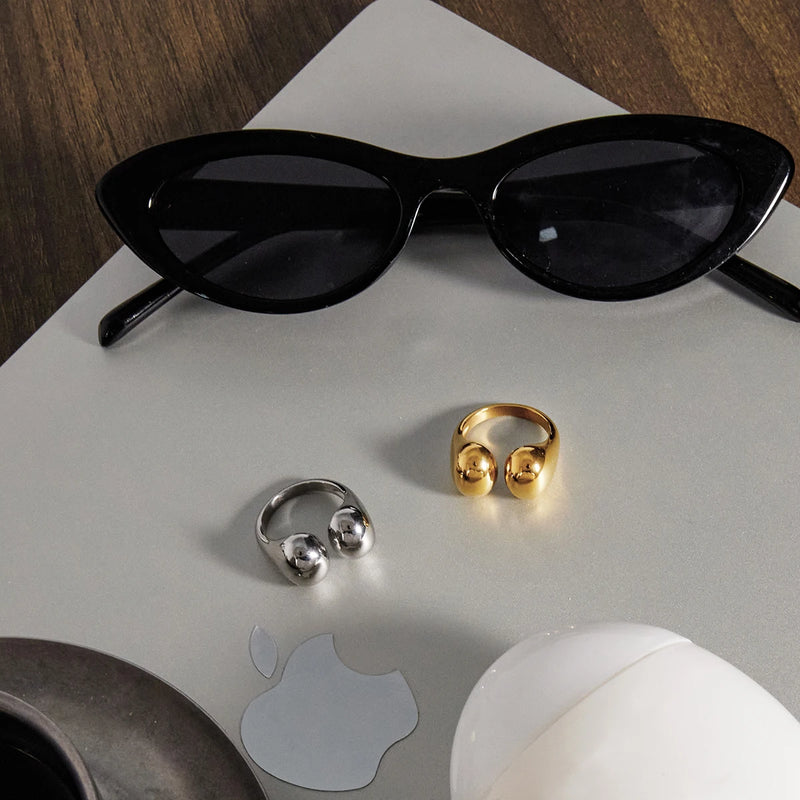 Both open rings on a pale surface beside black sunglasses