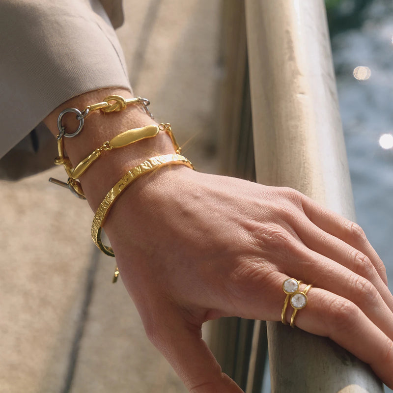 Pebble link bracelet worn on a wrist resting on a railing