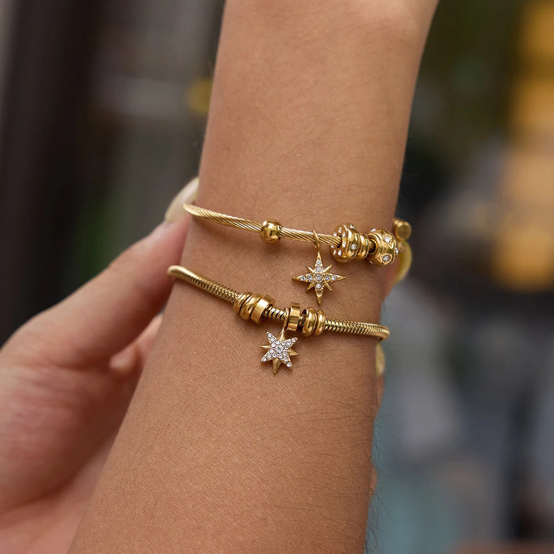 Two star charm bangles worn on a raised wrist