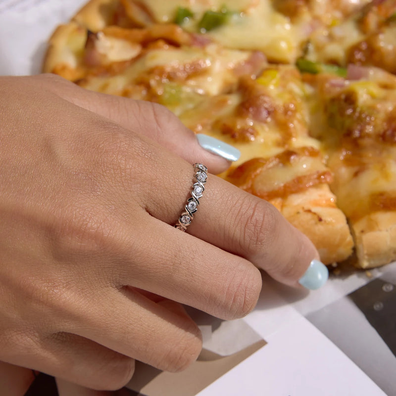 Crystal-set eternity ring worn on a hand beside a pizza