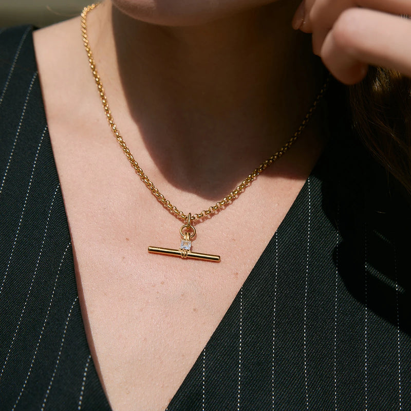 Gold-tone T-bar necklace worn at the collarbone