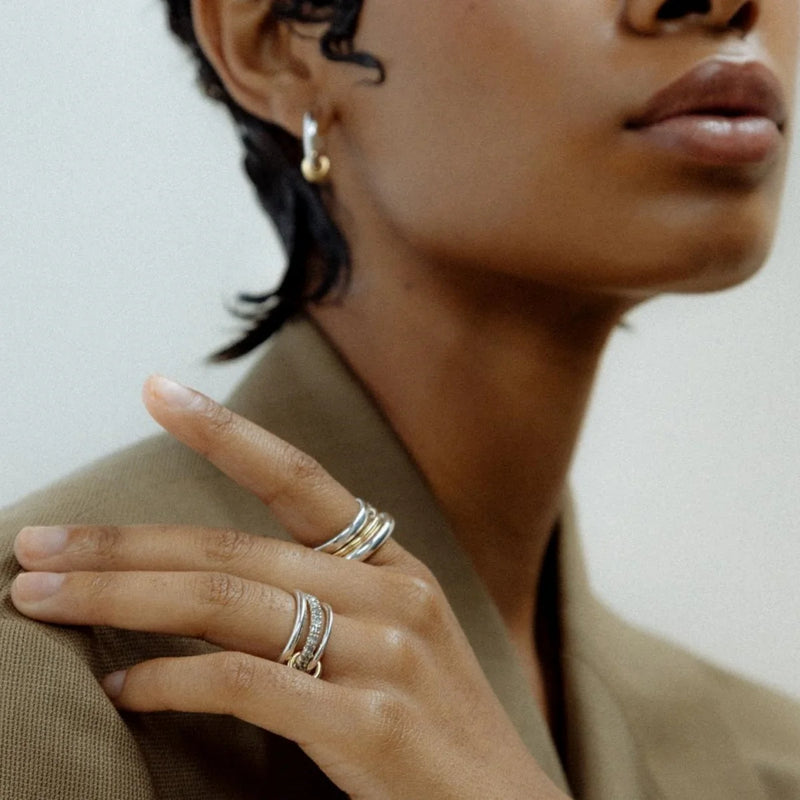 Triple-band rings worn on a hand raised to the chin