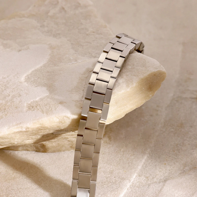 Silver-tone link bracelet draped over pale stone