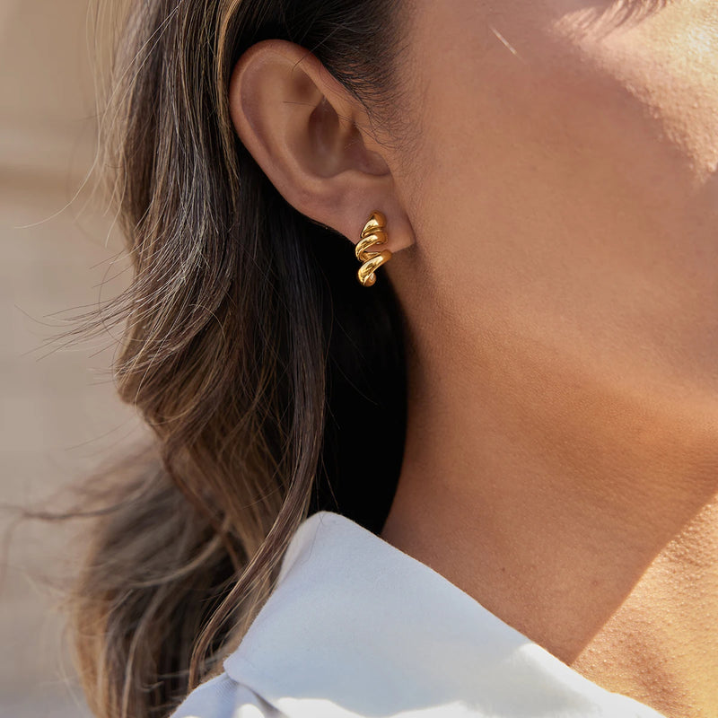 Spiral stud earring worn with a white collar in the frame