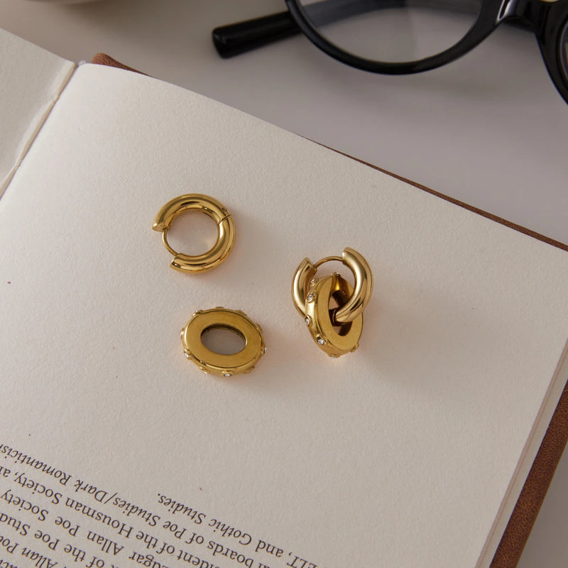 Pair of double circle earrings on a white card beside glasses