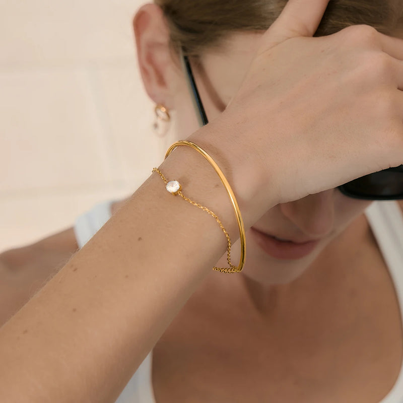 Bangle and chain worn on a wrist raised to the face