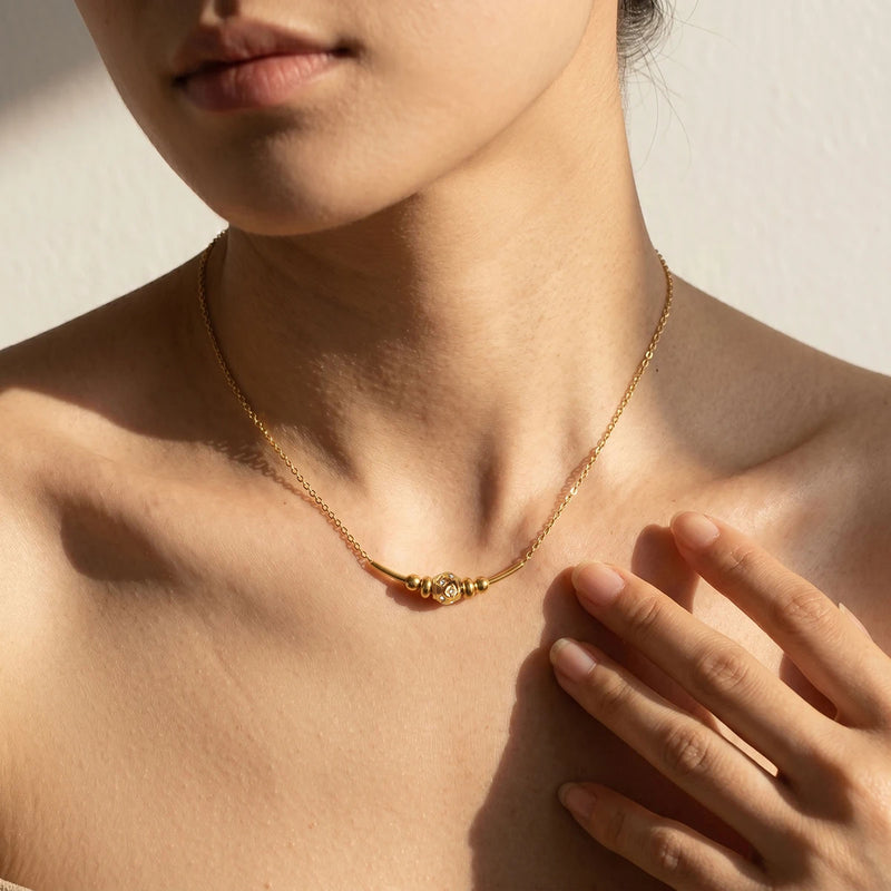 Beaded chain necklace worn at the collarbone, hand raised