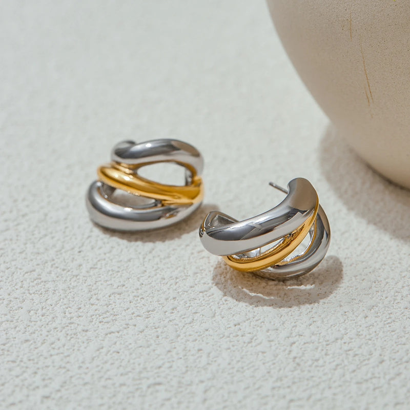 Crossover hoop earrings beside a rounded ceramic form