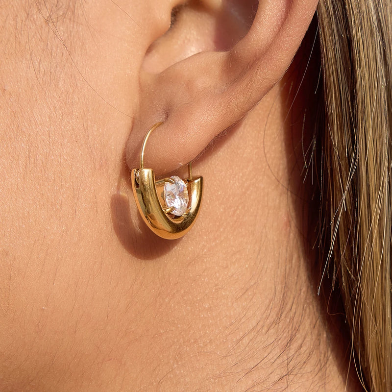 Chunky gold-tone crescent hoop with a clear crystal, worn on the ear