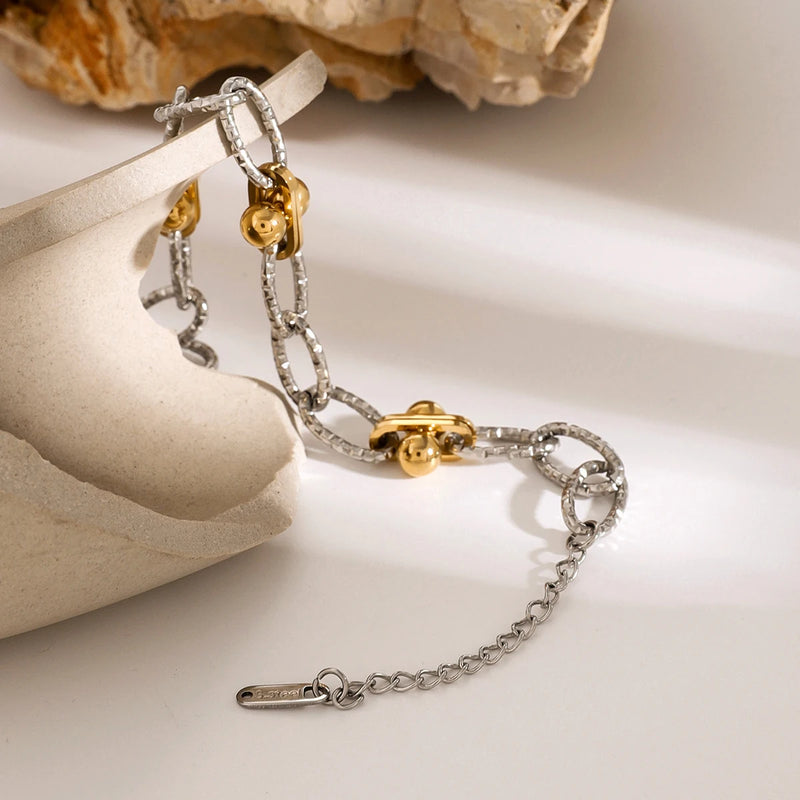 Chain bracelet with gold-tone links resting against a stone form