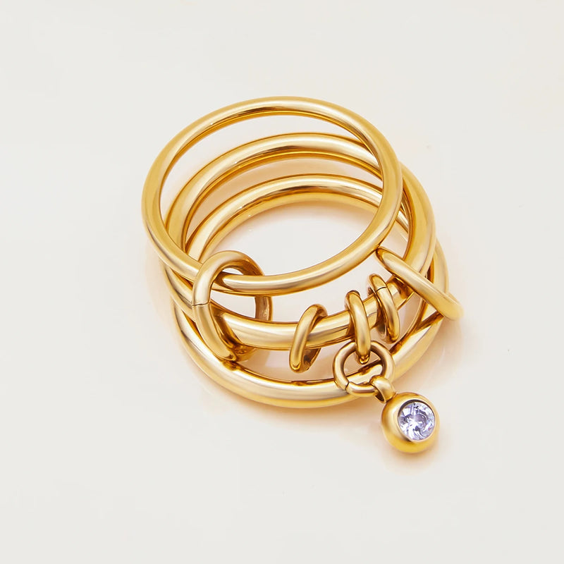 Three linked bands with a hanging crystal, standing on cream