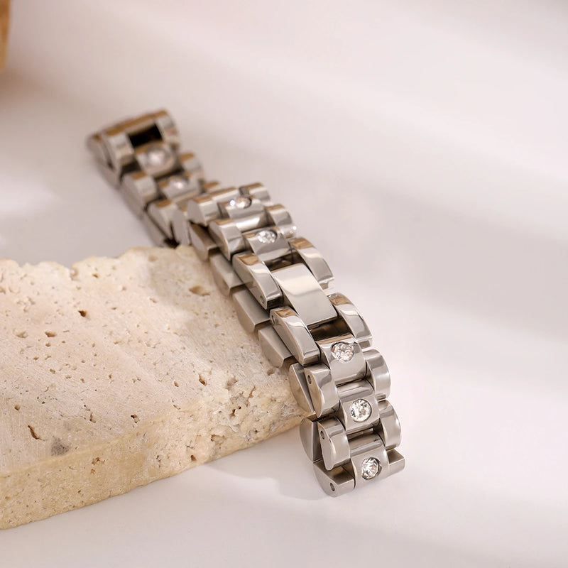 Watch-link bracelet propped against a pale stone