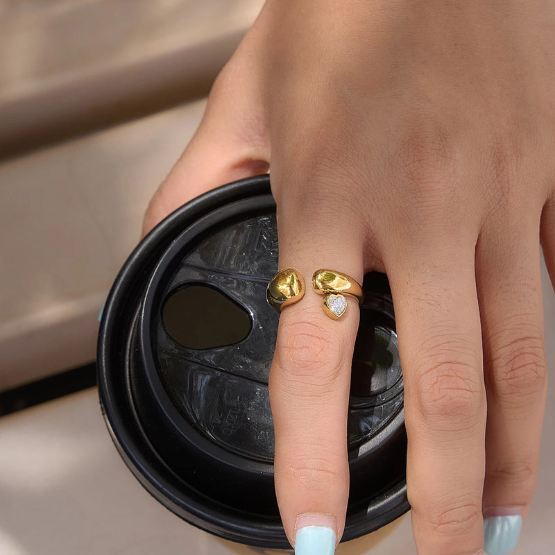 Heart stone ring worn on a hand resting on a cup lid