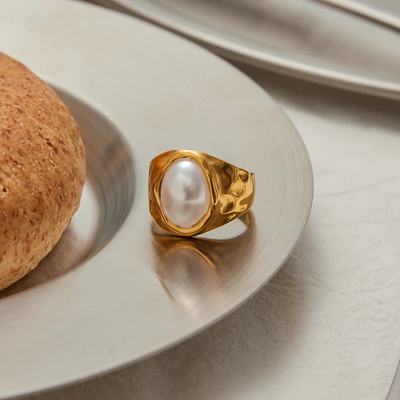 Opal-effect signet ring on a plate beside a bread roll