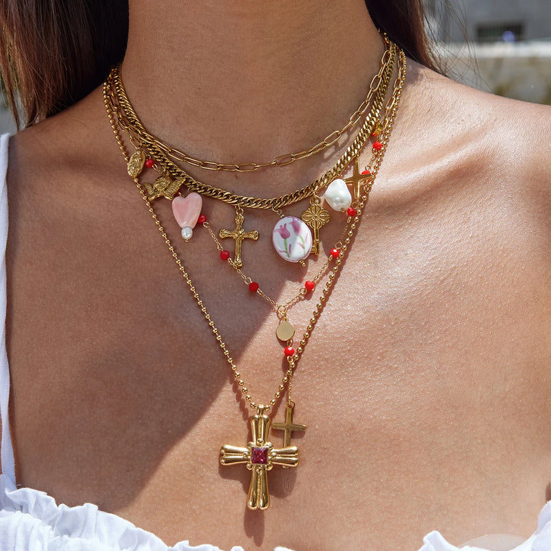 Cross and charm necklaces worn layered at the collarbone