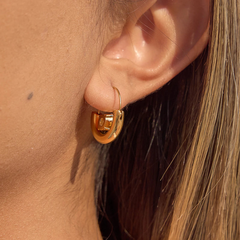 Smooth crescent hoop earring worn on the lobe, side view