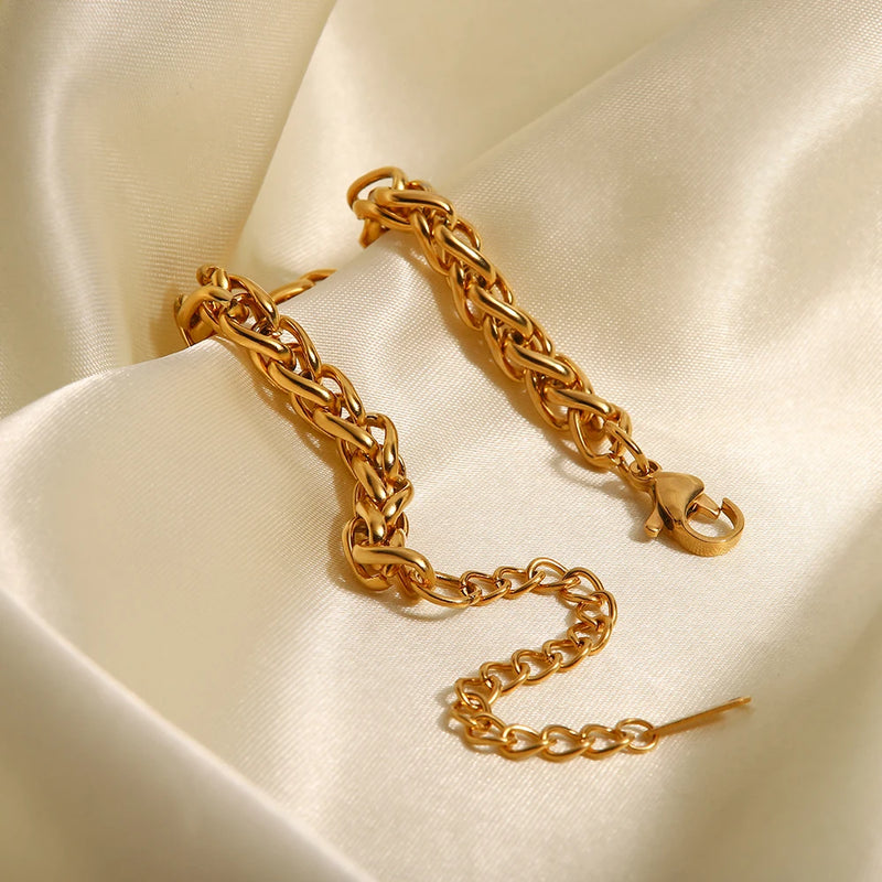 Wheat chain bracelet laid in an S-curve on cream satin