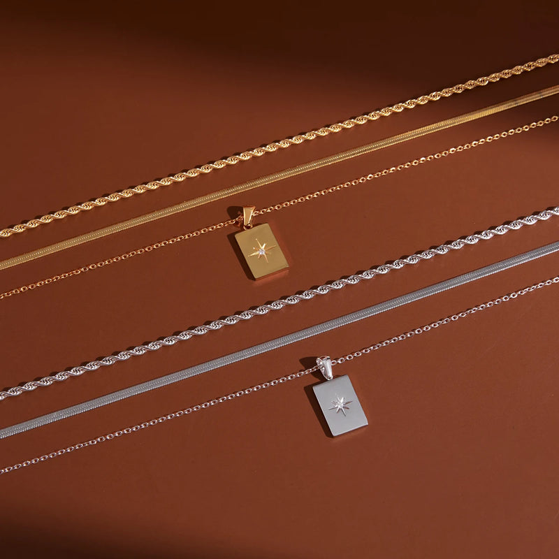 Two star tag necklaces laid flat on a warm brown background