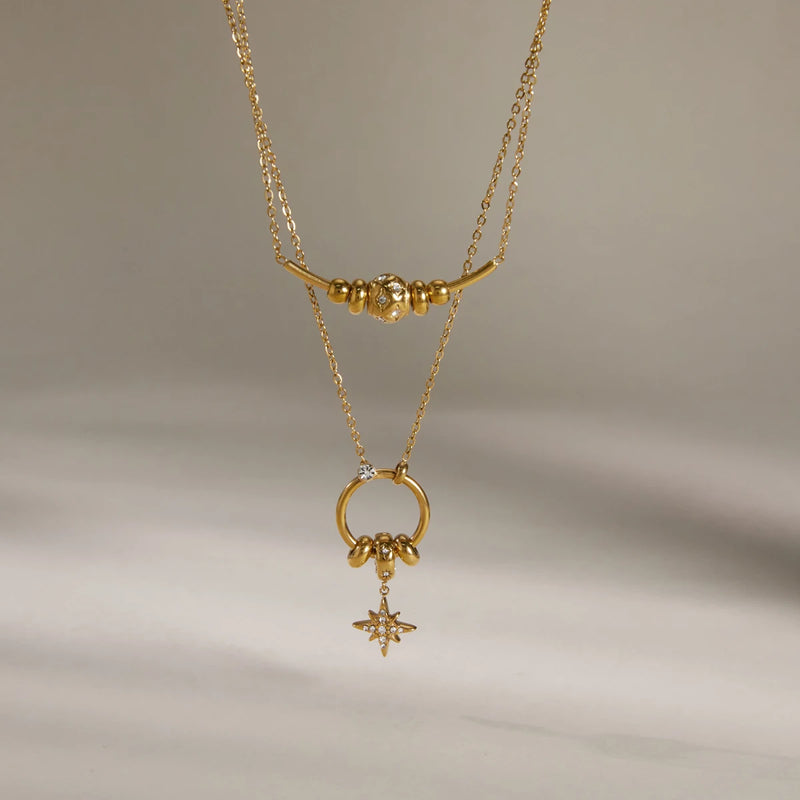 Layered chains with a hanging star charm on a cream background