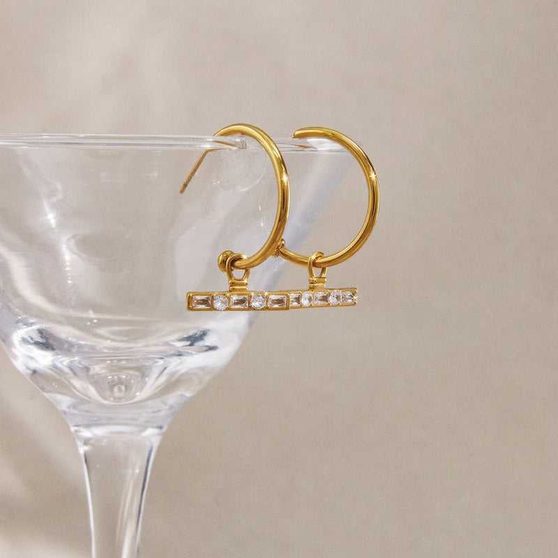 C-hoop T-bar earrings hooked over a clear glass stem