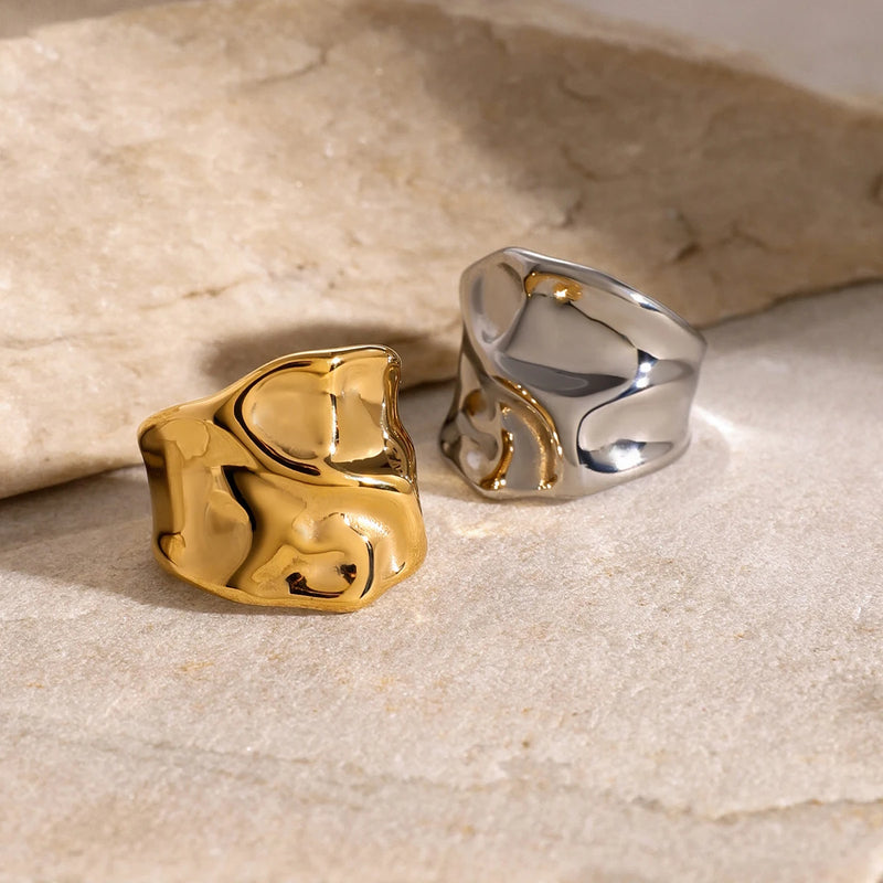 Gold-tone and silver-tone molten band rings on a pale stone