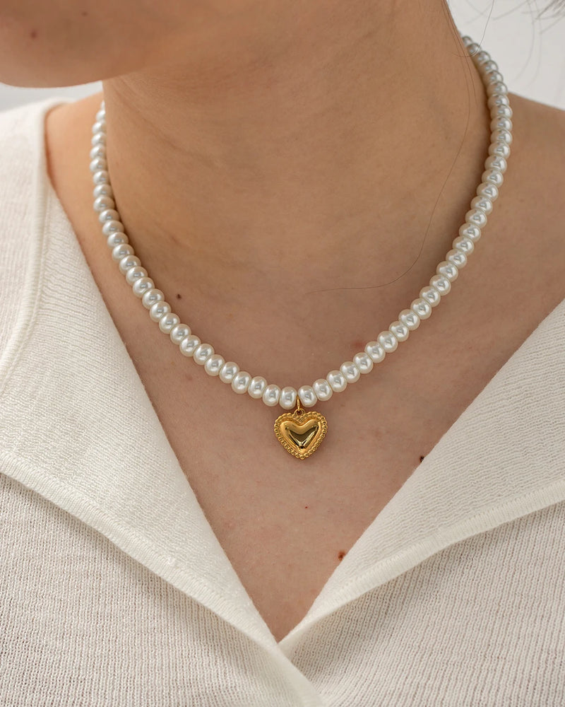 Pearl beaded necklace with a heart pendant worn with a white collar