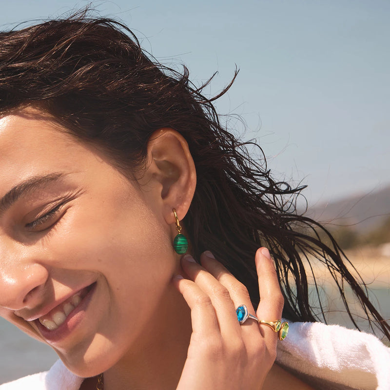 Model on the beach wearing a green stone drop earring