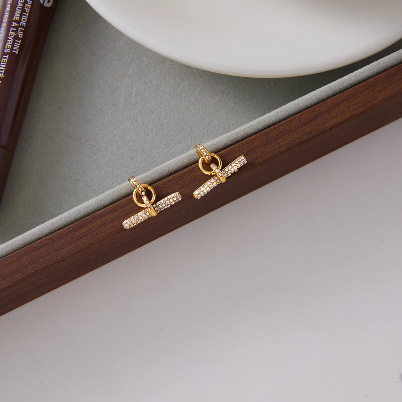 Pair of crystal-set T-bar earrings on a dark wooden edge