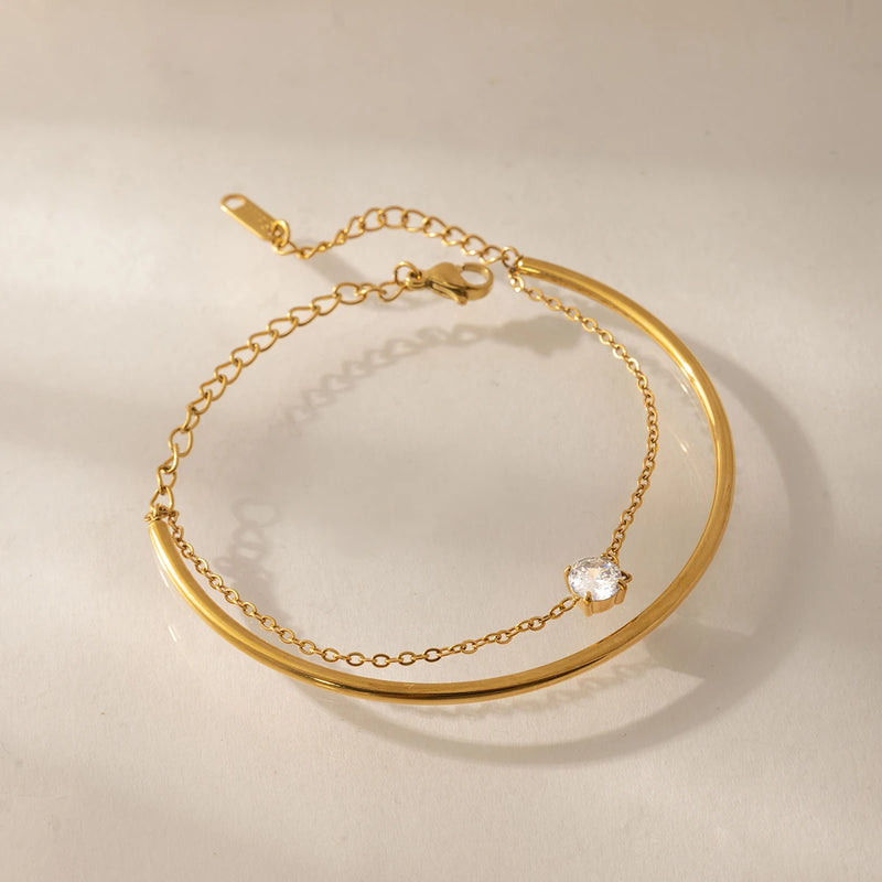 Bangle and chain bracelet arranged in a loop on cream fabric