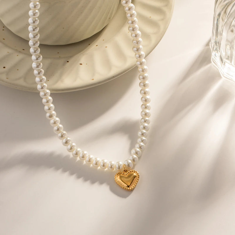 Pearl beaded necklace with a gold-tone puffed heart on a cream surface