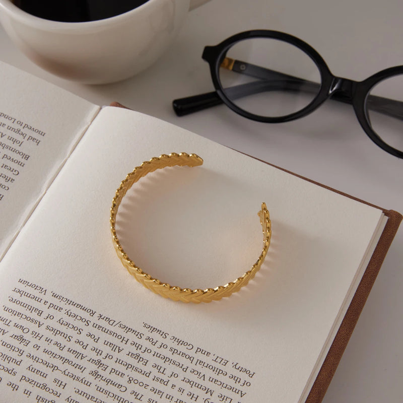 Chevron cuff standing on an open book beside glasses and coffee