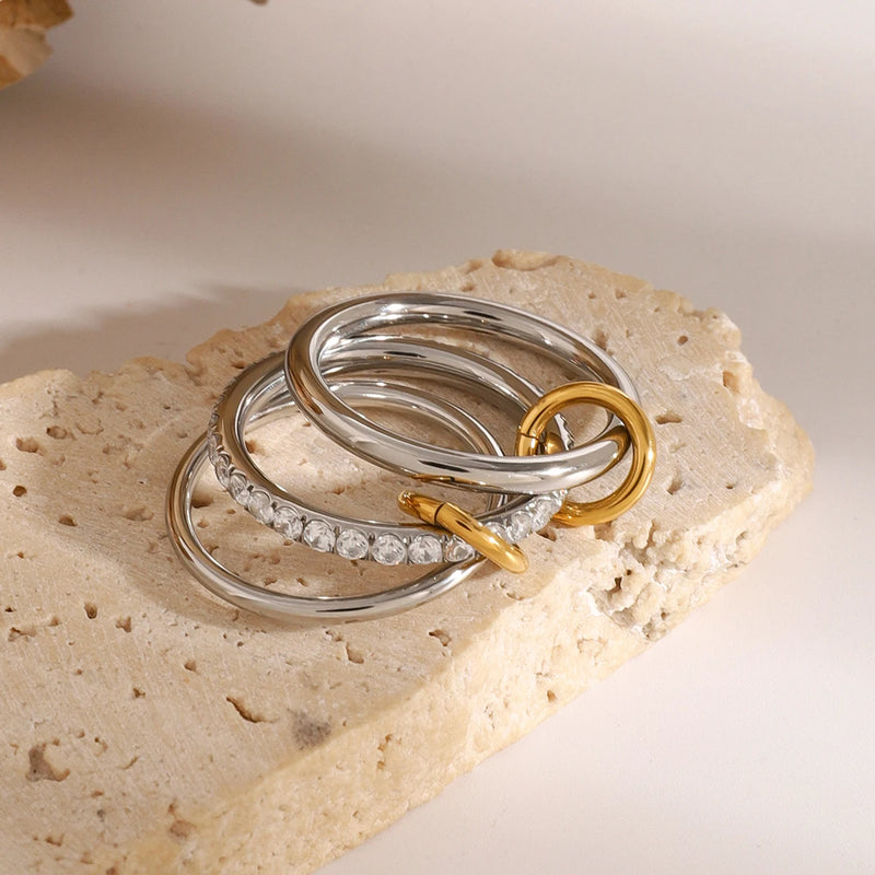 Two interlocking triple-band rings resting on pale stone