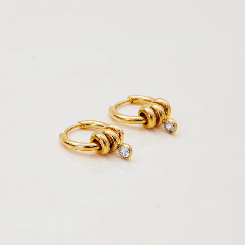 Pair of coiled huggie hoops with crystal drops on cream