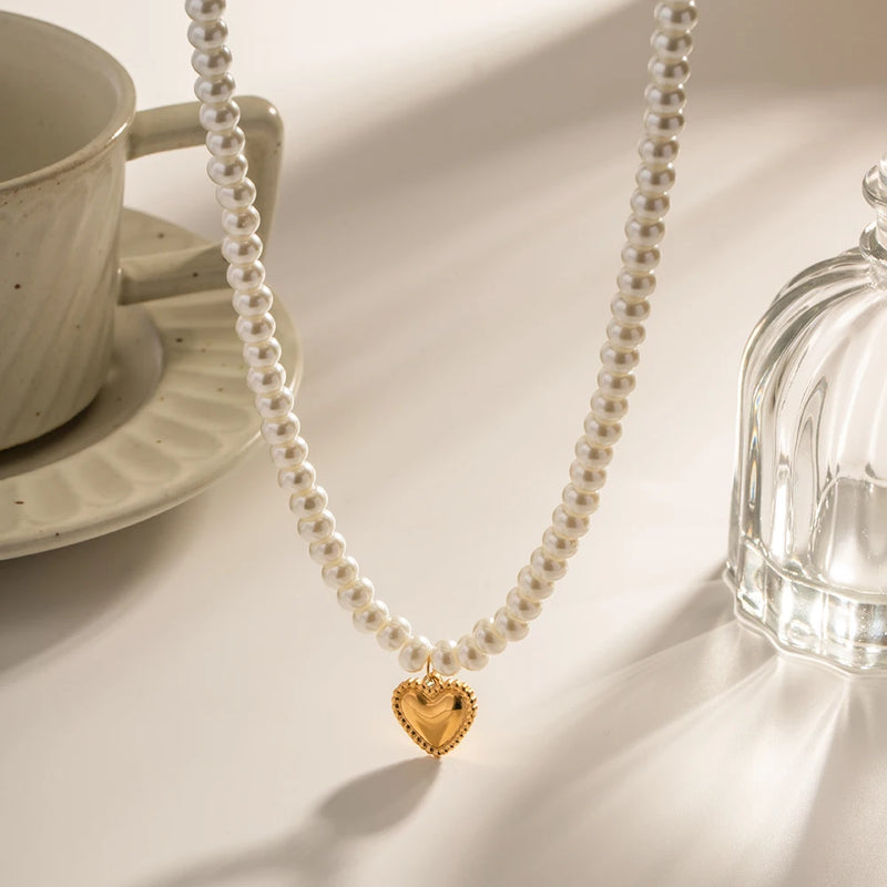 Pearl necklace with a heart pendant beside a cup and saucer