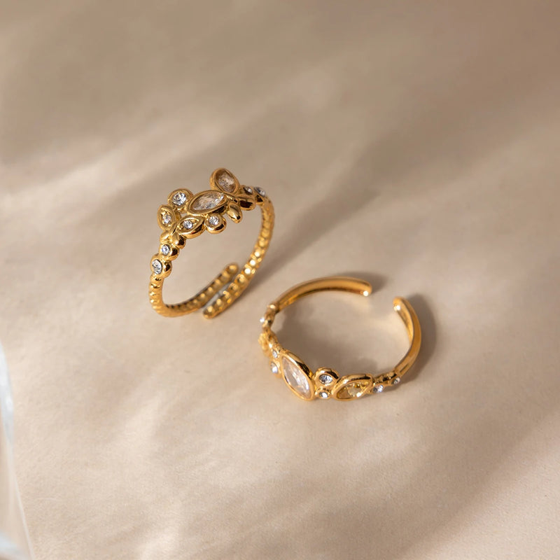 Two open crystal-set rings on a soft cream fabric background