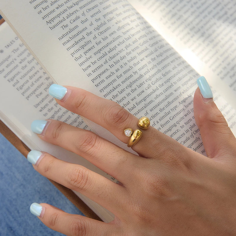 Heart stone open ring worn on a hand holding an open book