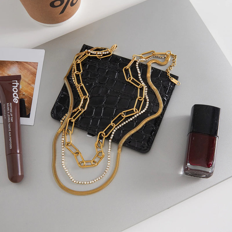 Marielle Triple-Layer Chain Necklace laid out beside a bag and cosmetics