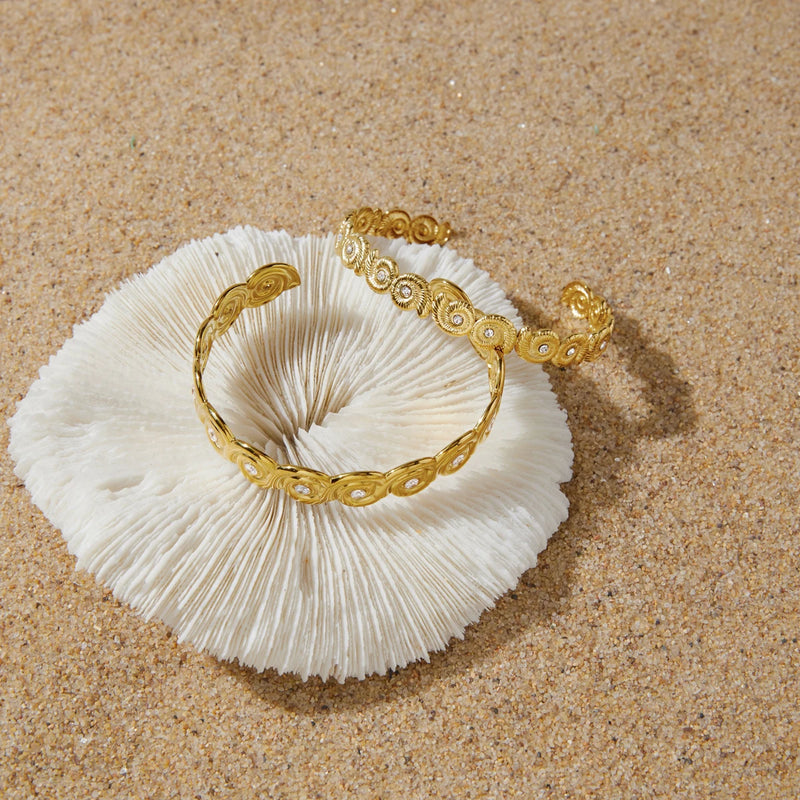 Spiral shell cuff resting on a white coral on sand