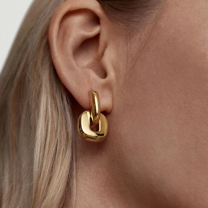 Gold-tone chunky link earring worn on the ear, side view