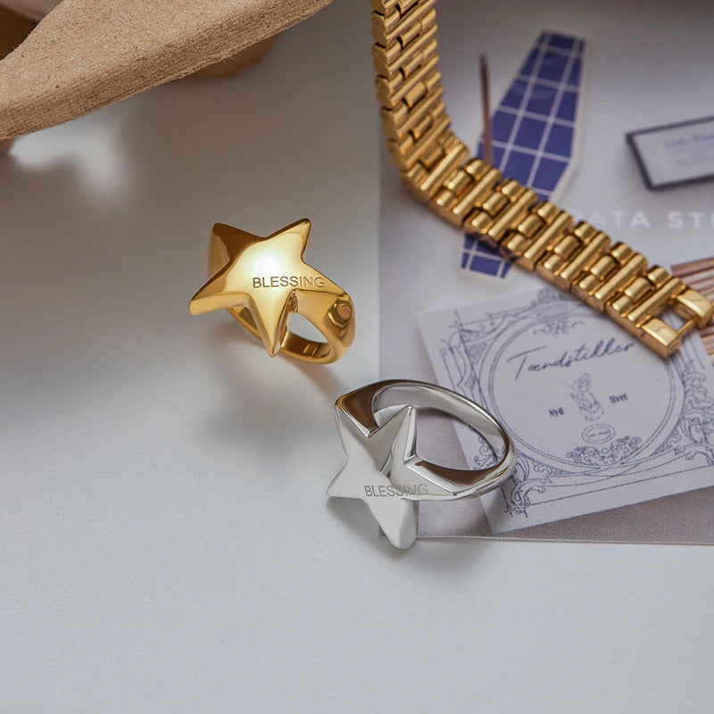 Gold-tone and silver-tone star rings on a desk with a chain strap