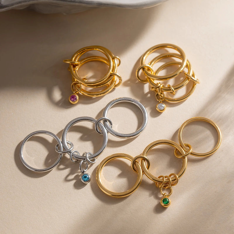 Several linked charm rings in gold and silver tone on cream
