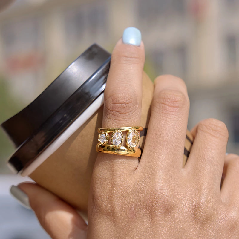 Antoinette Three-Stone Double Band Ring in gold-tone, worn while holding a cup