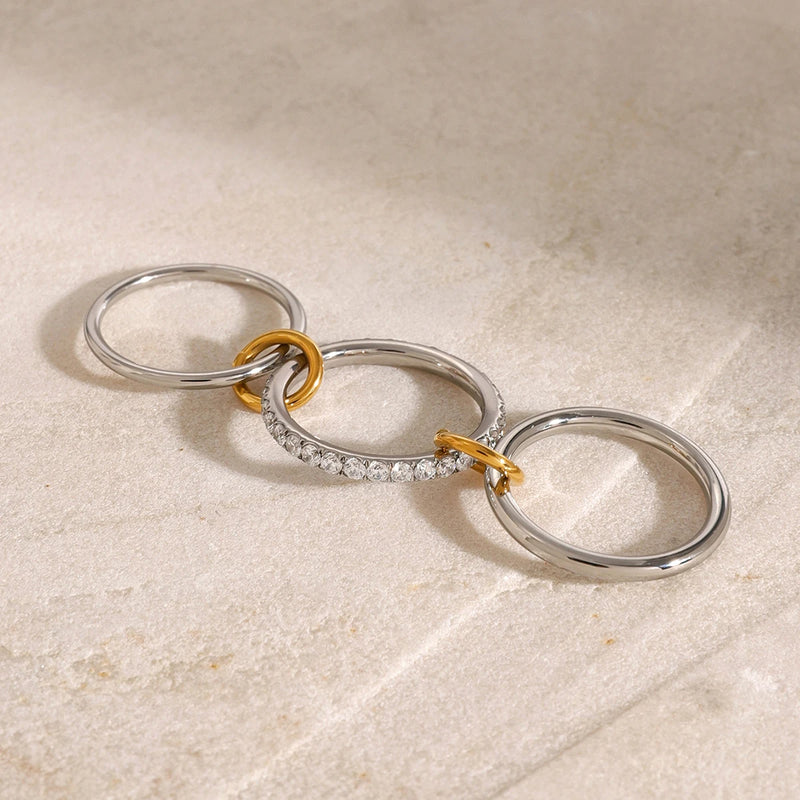 Interlocking triple-band ring opened flat on a pale surface