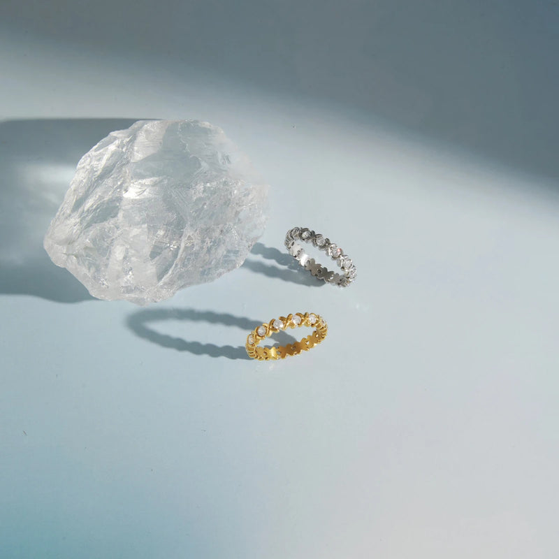 Gold-tone and silver-tone eternity rings beside a clear crystal