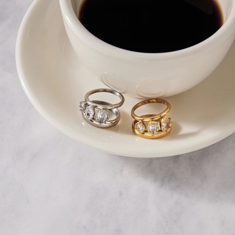 Antoinette Three-Stone Double Band Ring in gold-tone and silver-tone on a saucer