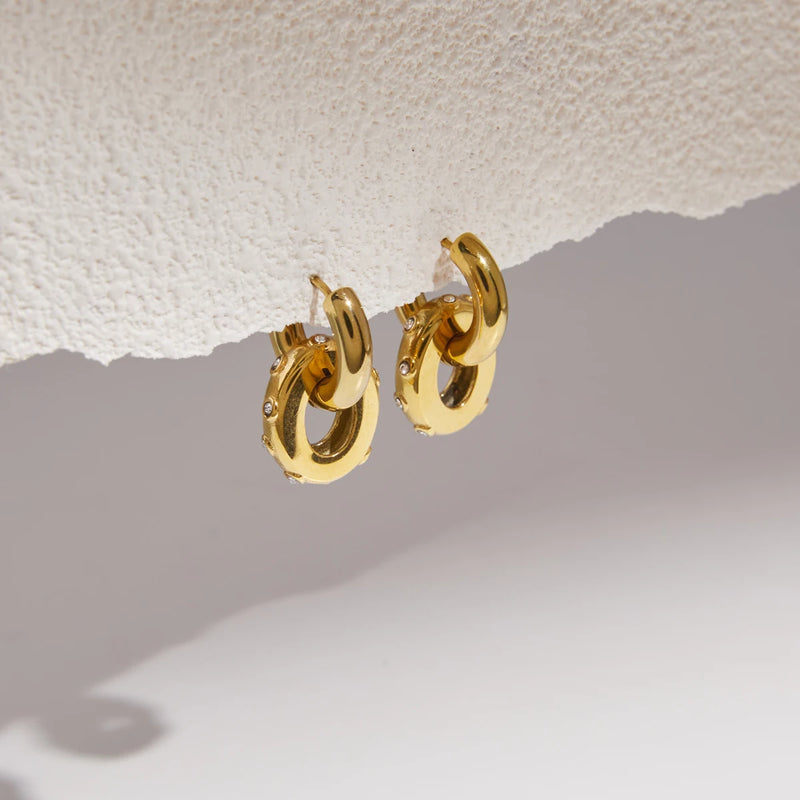 Two studded double circle earrings on a textured white surface